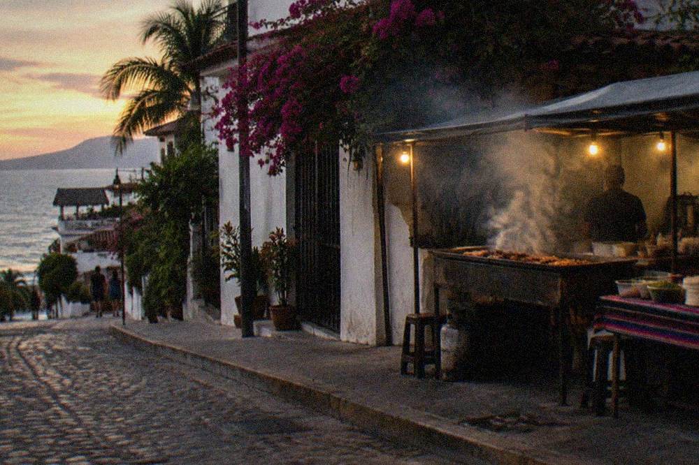 Taco stand grilling meat in the open air on a city street at dusk