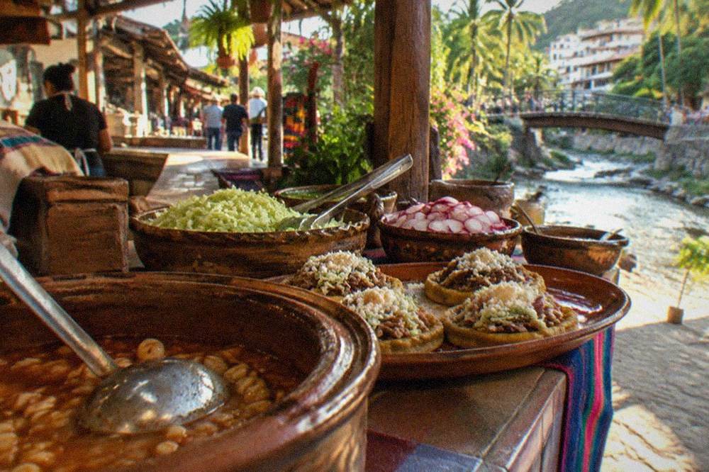 Colorful street food cart with sopes and fresh toppings on a Puerto Vallarta sidewalk