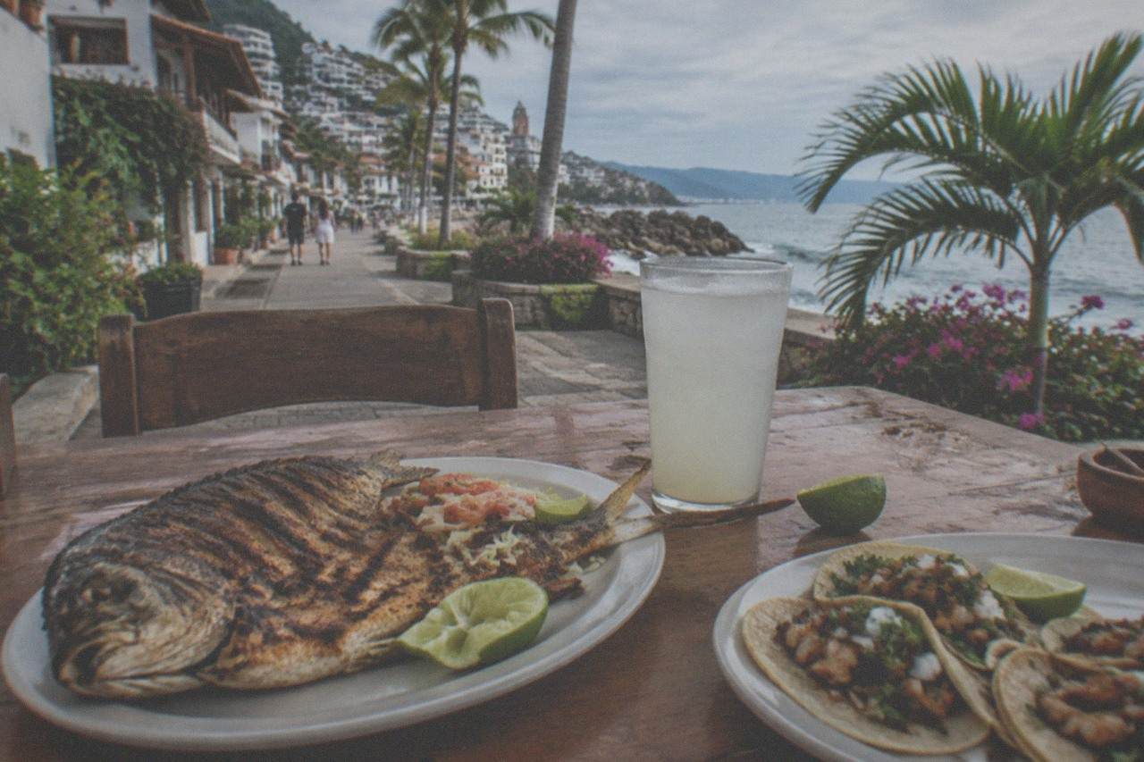 Grilled fish and fresh tacos on an outdoor table beside a Puerto Vallarta street