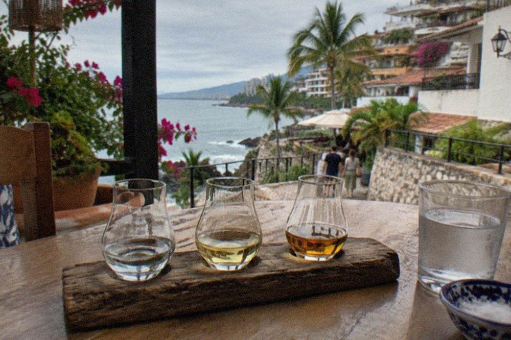 A flight of tequila glasses arranged on a rustic wooden tasting table