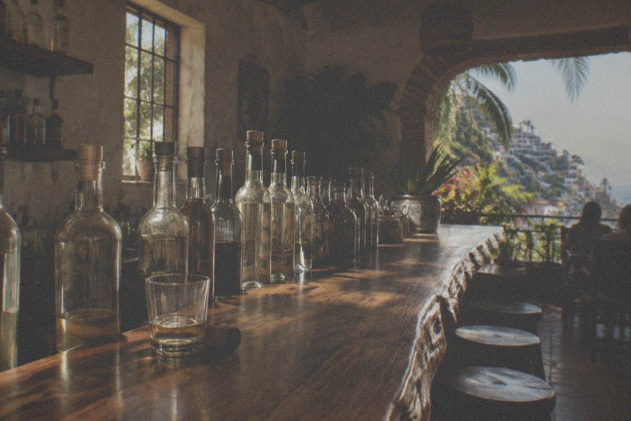 Bottles of agave spirits lined up on a wooden bar counter