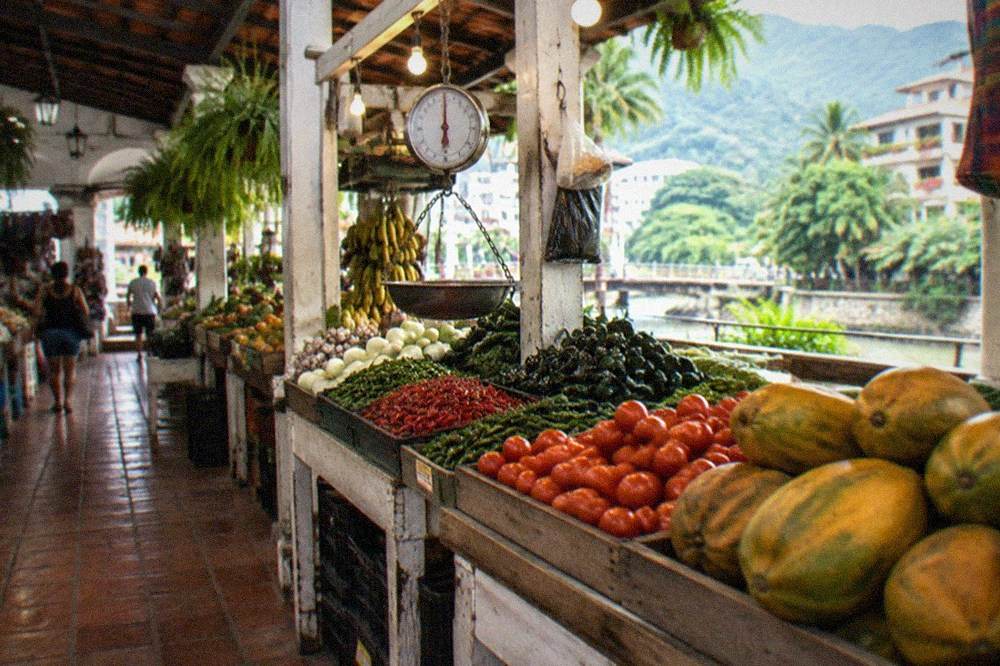 Market stall displaying chiles, tomatoes and fresh fruit under warm lights