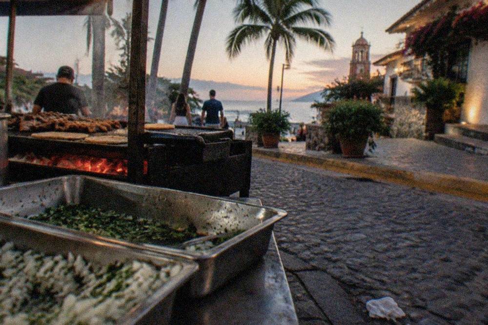 Street taco stand with grilled meat, chopped onion and cilantro in metal trays