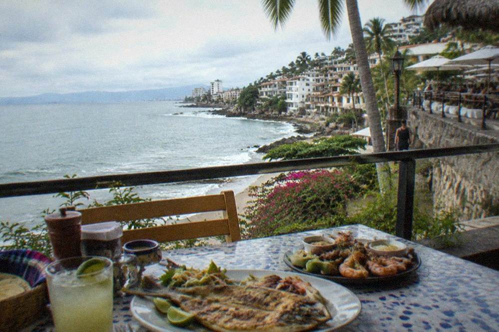 Grilled whole fish and seafood platters on a restaurant table overlooking the bay