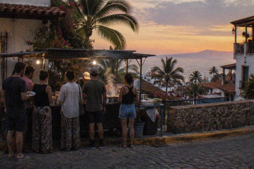 Guided walking tour group gathered at a street food stand in Old Town Puerto Vallarta