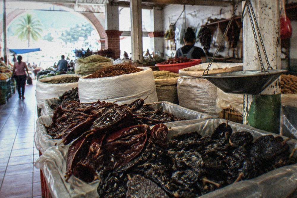 Colorful bins of dried chiles and spices at an indoor Mexican market stall