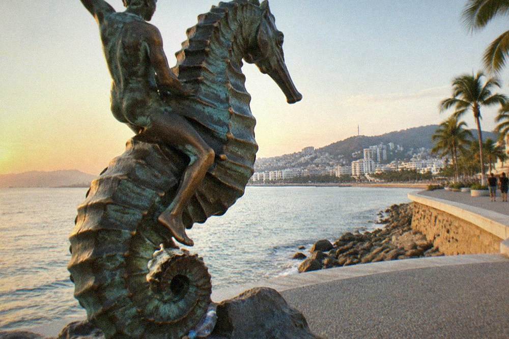 Bronze sculpture of a boy riding a seahorse on an oceanfront promenade