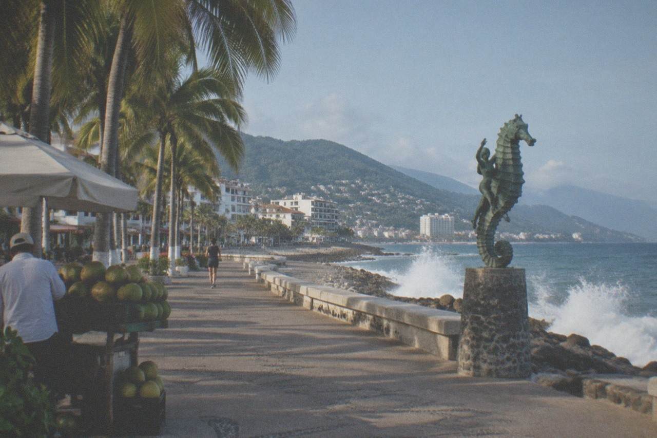 Oceanfront boardwalk with palm trees, sculptures and waves along the Puerto Vallarta shoreline