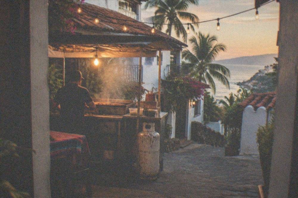 Evening street food stall with a grill, steam and warm string lights on a side street