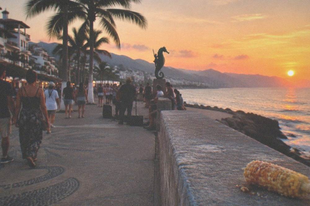 Crowded seaside promenade at sunset with performers and strolling visitors