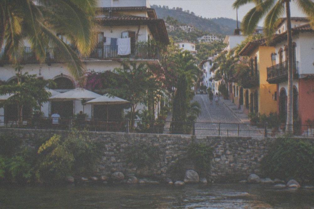 Cobblestone street with cafe tables and colorful buildings leading away from the river