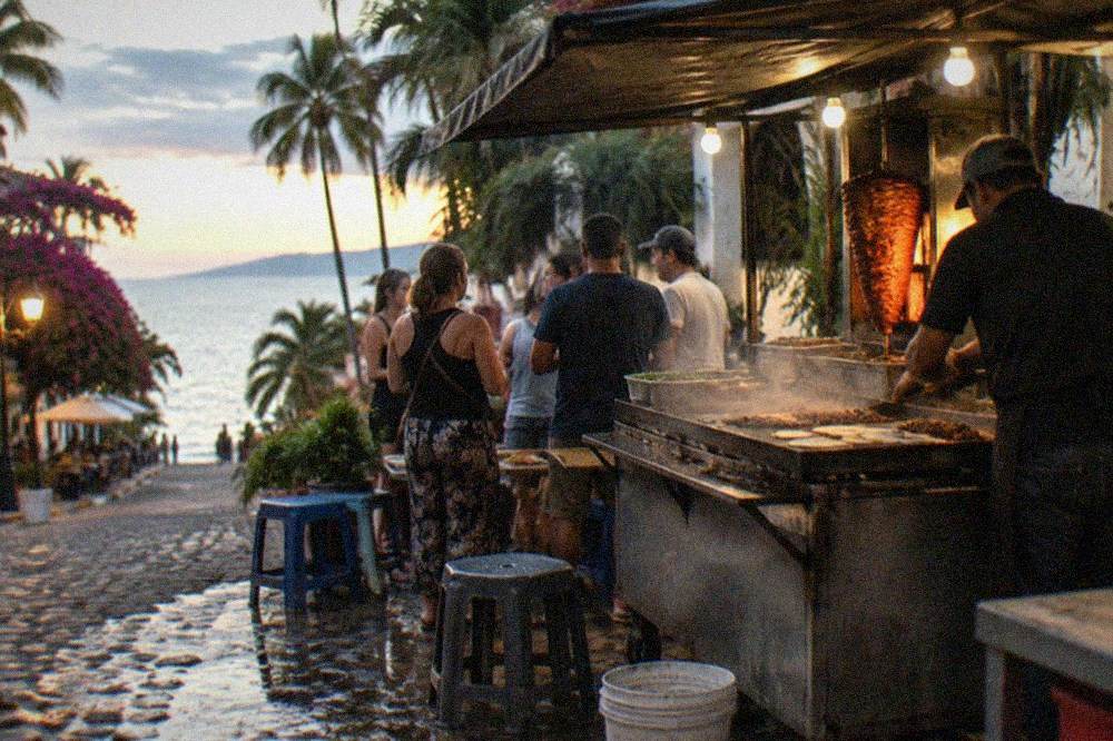 Guided walking tour group gathered at a taco stand in a Puerto Vallarta neighborhood