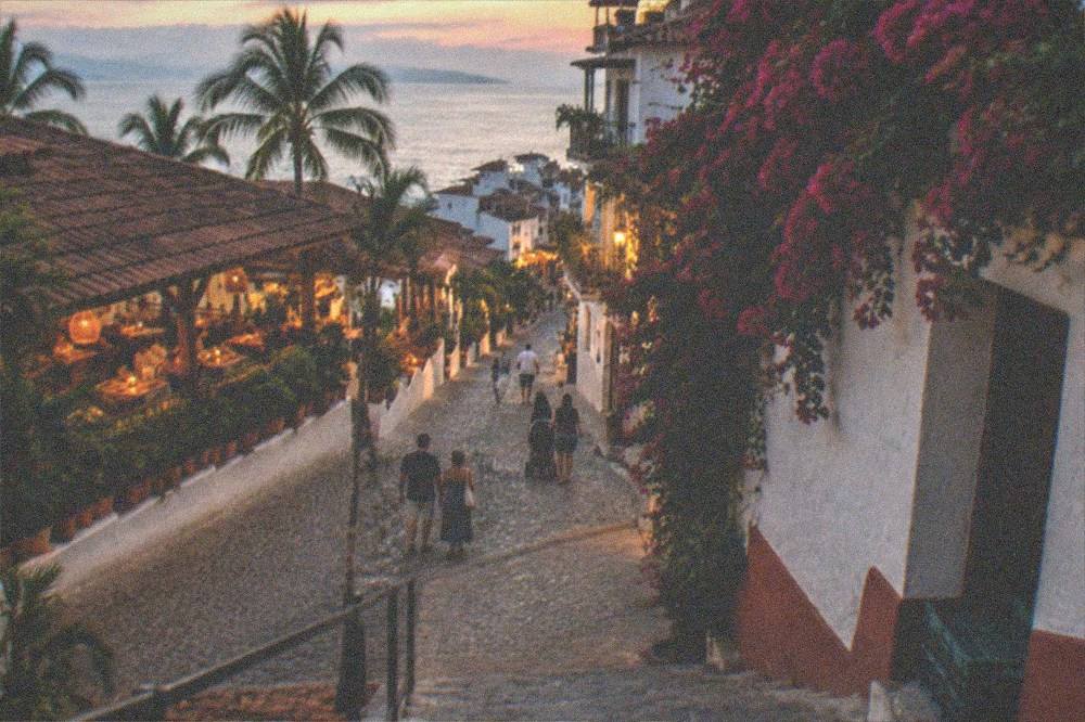 Evening street scene with lit restaurants and people walking a cobblestone street
