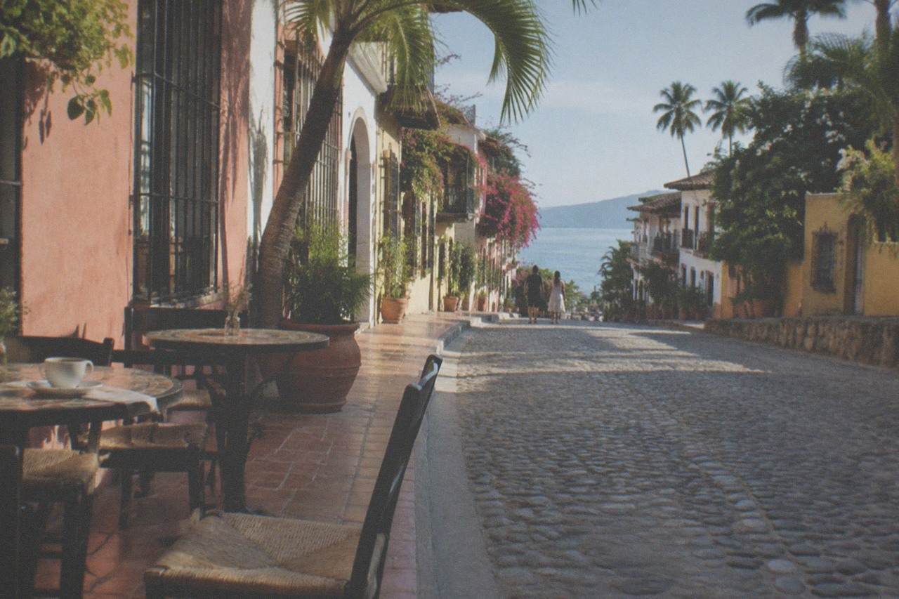 Cobblestone street in Old Town Puerto Vallarta with cafe tables and colorful building facades