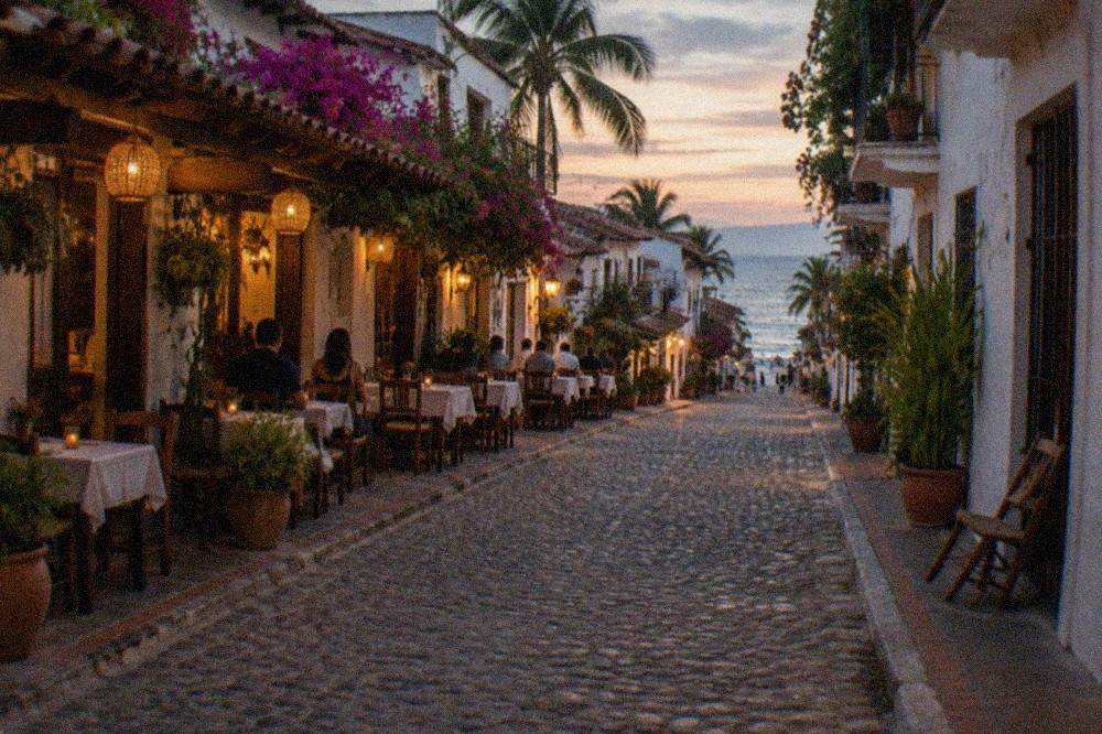 Evening view of a pedestrian street in Old Town Puerto Vallarta with lit restaurant fronts and diners at outdoor tables