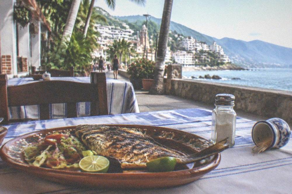 Plated seafood dish with grilled fish and lime on an outdoor restaurant table in Old Town Puerto Vallarta