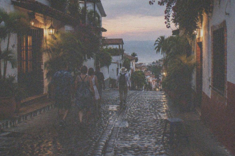 Small group of diners walking a cobblestone street in Old Town Puerto Vallarta at dusk following a guide