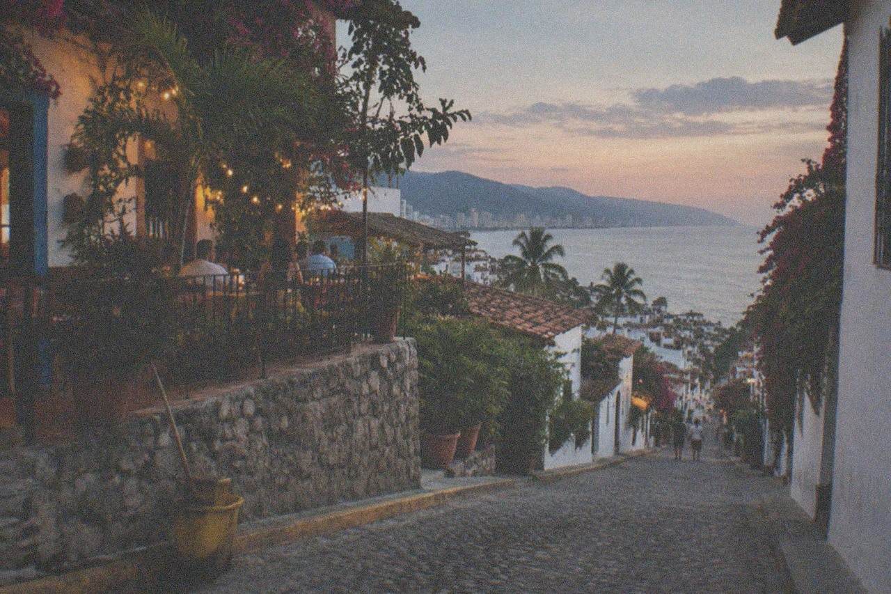 Cobblestone street in Old Town Puerto Vallarta with restaurant tables set out under string lights in the early evening