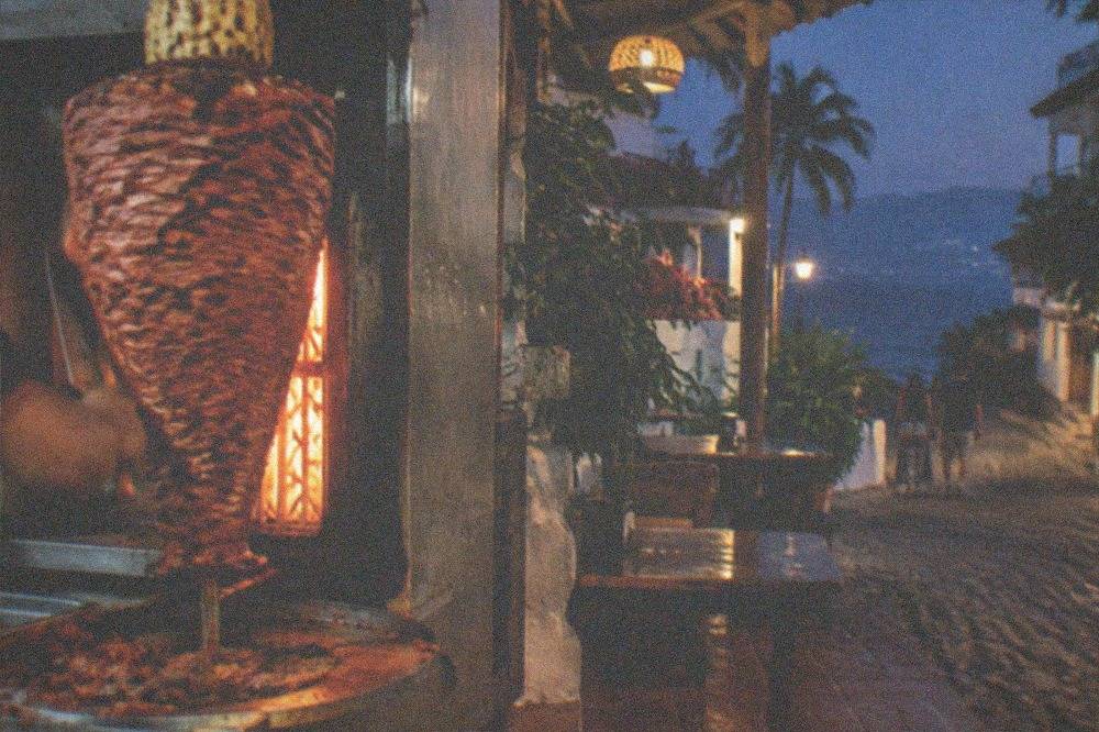A vertical trompo spit of al pastor meat with pineapple on top at a taqueria