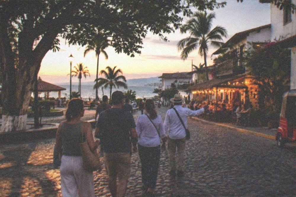 A small group walking down a cobblestone street in Old Town Puerto Vallarta at dusk