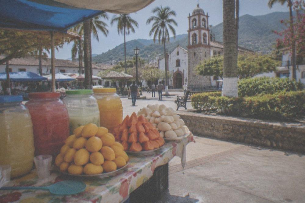 A market stall displaying fresh fruit and aguas frescas in jars