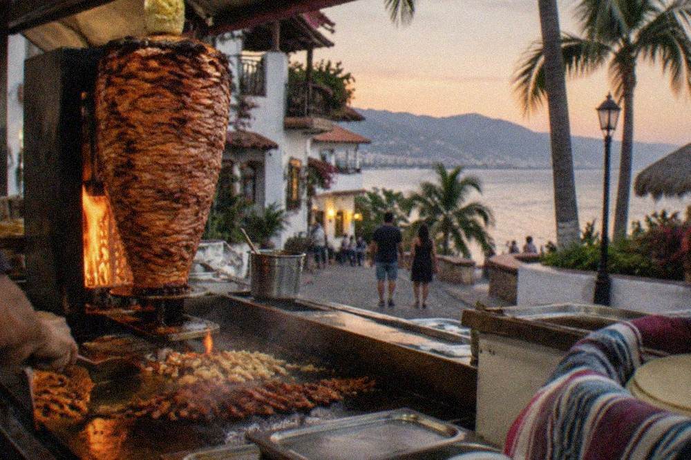 Al pastor trompo spinning beside a hot grill at a taco stand
