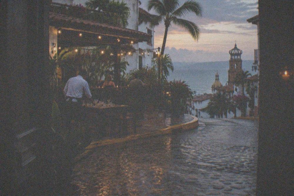 An evening street in Puerto Vallarta with string lights over a cantina terrace and a cobblestone corner