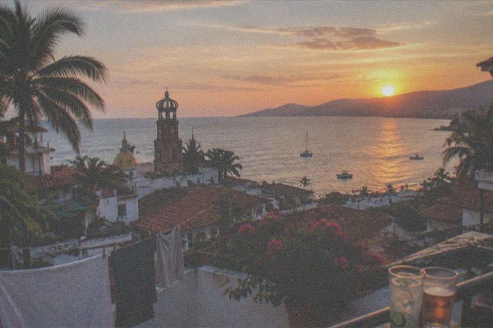 Rooftop terrace overlooking red tile rooftops and the bay at sunset