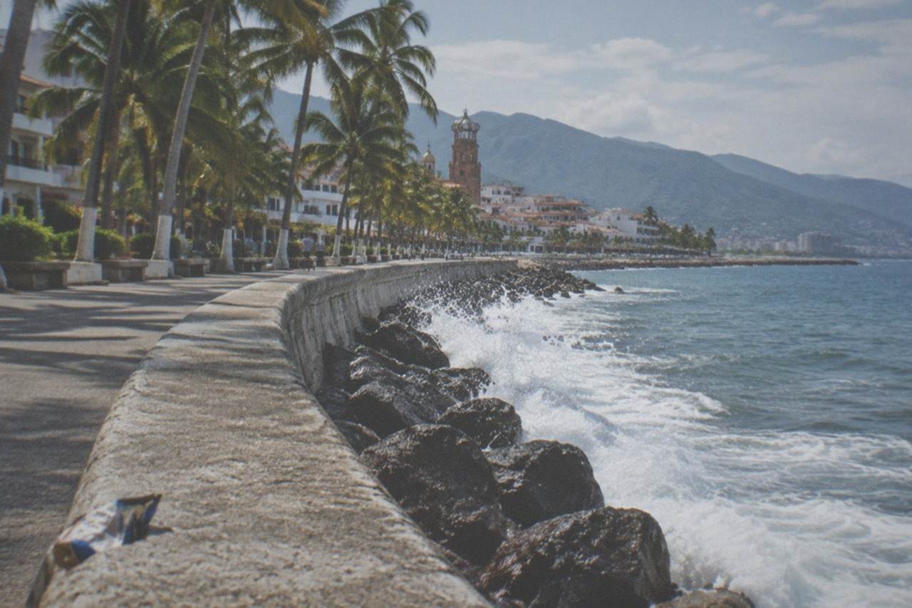 Oceanfront boardwalk in Puerto Vallarta with palm trees and the bay in the background