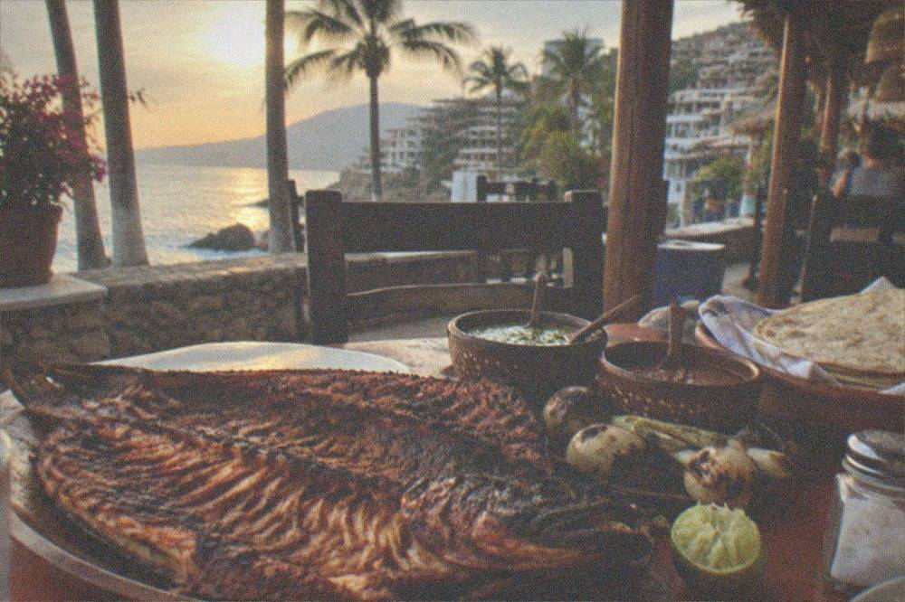 Whole grilled fish served open on a platter with lime wedges, salsas and warm tortillas
